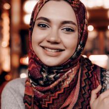 Beautiful an Arabian girl with a headscarf on her head posing in a cafe, looking at the camera and smiling
