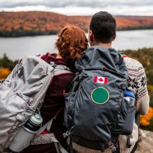 Young couple sit on rock looking at view of the fall colours and river. Canada