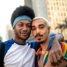 Male couple embracing during gay pride parade. LGBTQ