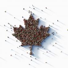 Aerial view of a group of people gathered together in the shape of a Canadian maple leaf. 