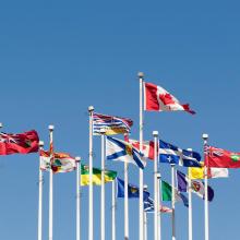 Le drapeau du Canada et ceux des provinces et territoires flottent au vent à la place du Canada à Vancouver.