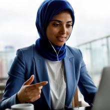Young woman wearing a hijab sitting in front of a laptop having a conversation by video